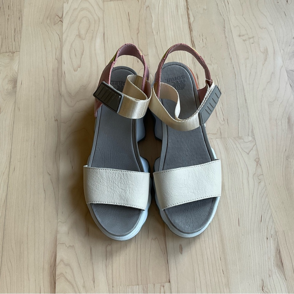 Sorel sandal in cream with a pink and yellow back strap.